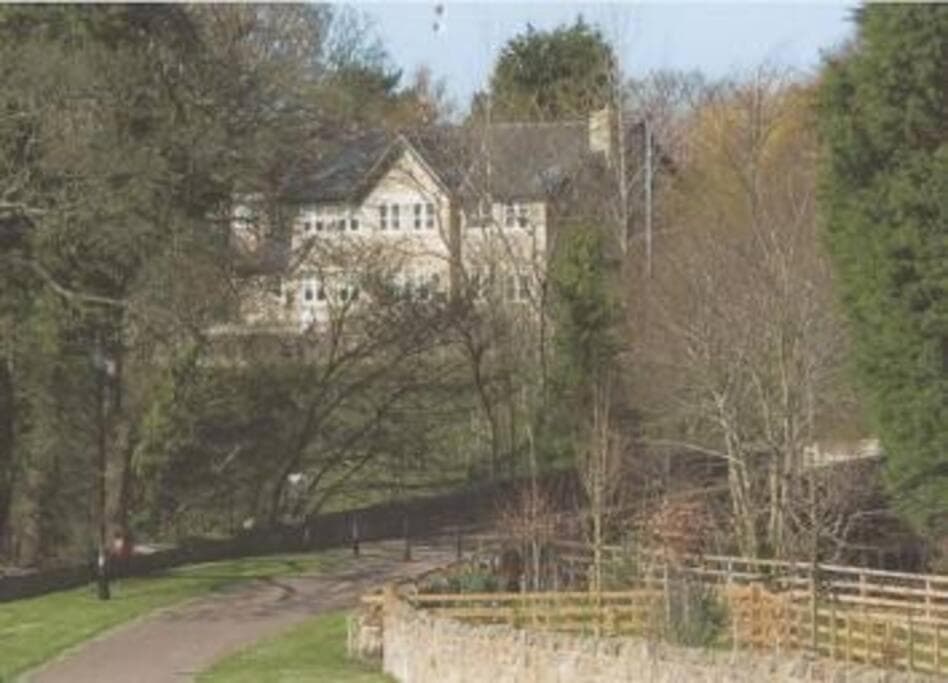 Alnside Lodge seen beyond trees and a nearby path