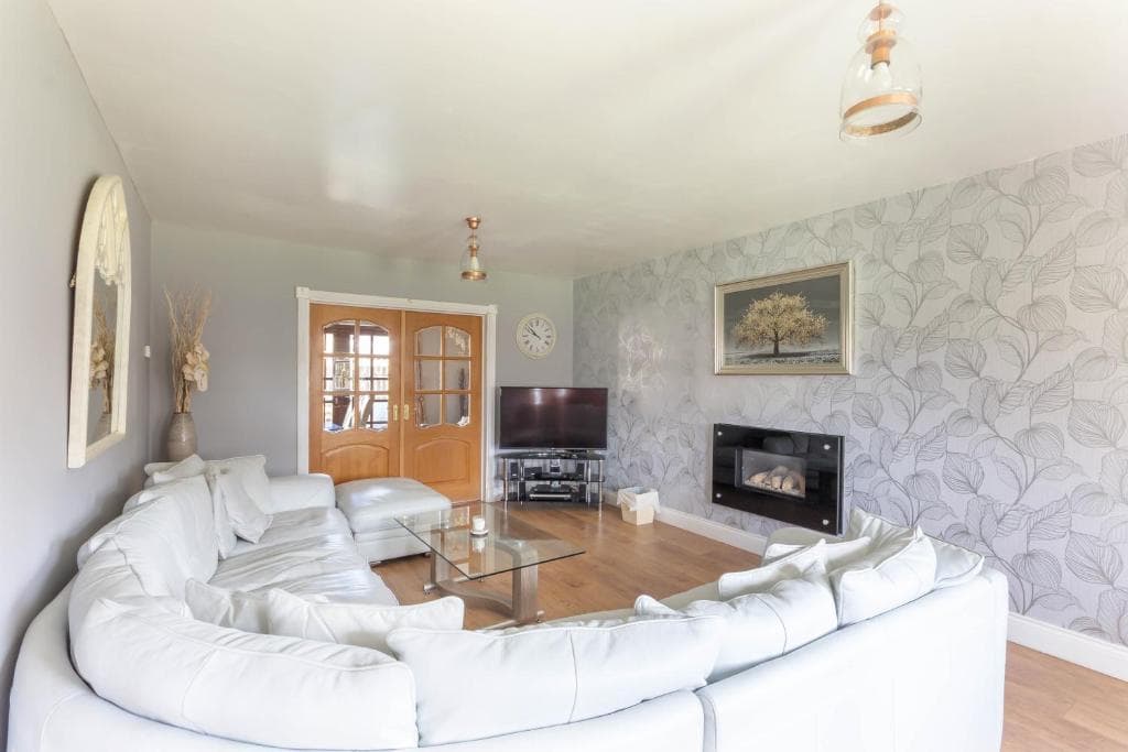 The lounge at Alnside Lodge, with sofas, a television and fireplace